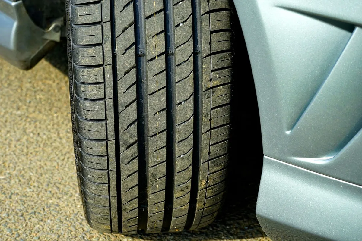 Close-up of a car tire and wheel arch on a paved driveway