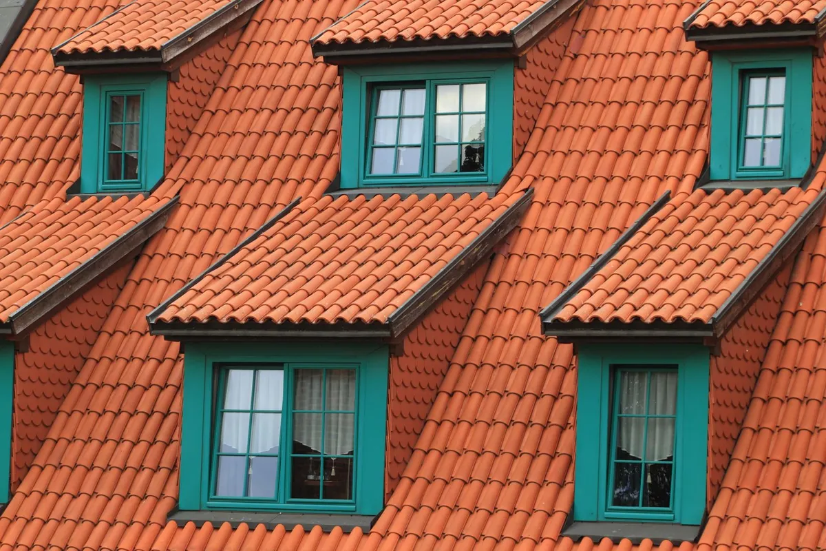 Close-up of a terracotta tiled roof with green-framed dormer windows
